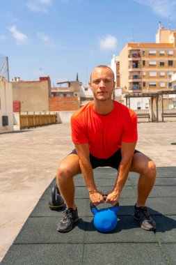 Spor adam ağırlıkları açık havada geri egzersiz egzersiz yapıyor. Erkek atlet egzersiz, sokakta bir kol kettlebell satır yapıyor