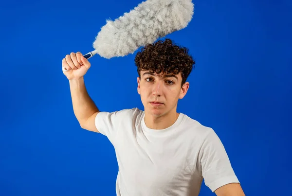 Blanke jongeman die grappig poseert met een schoonmaakstofdoek op een blauwe studioachtergrond. Reinigingsconcept — Stockfoto