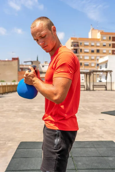 Kafkasyalı genç adam sokakta çan ağırlıklarıyla çömeliyor forma girmek ve vücudu hakkında iyi hissetmek için antrenman yapıyor. Sağlıklı yaşam konsepti.
