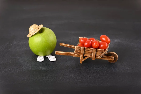 An apple and antique barrow with cherry tomatoes, conceptual photo.