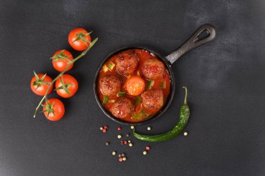 Koyu arkaplanda tencerede domates soslu köfte..