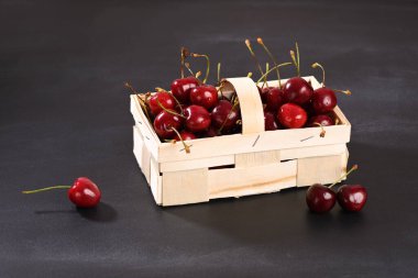 Kırmızı kiraz sepetinde koyu arkaplanda..