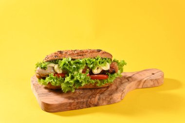 Bol yeşil salata ve kızarmış sosisli sandviç..