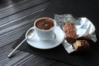 Koyu arkaplanda çikolatalı waffle ve kahve bardağı.