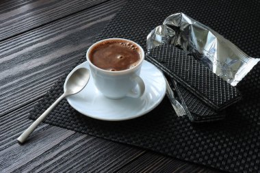 Cup with coffee and black waffles on the table
