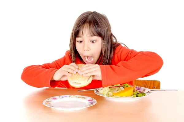 Dziewczyna, rozdarty między hamburguer i warzywa — Zdjęcie stockowe