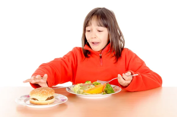 Chica desgarrada entre hamburguesa y verduras — Foto de Stock