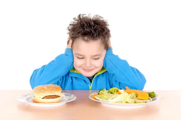 Niño desgarrado entre hamburguesa y verduras — Foto de Stock