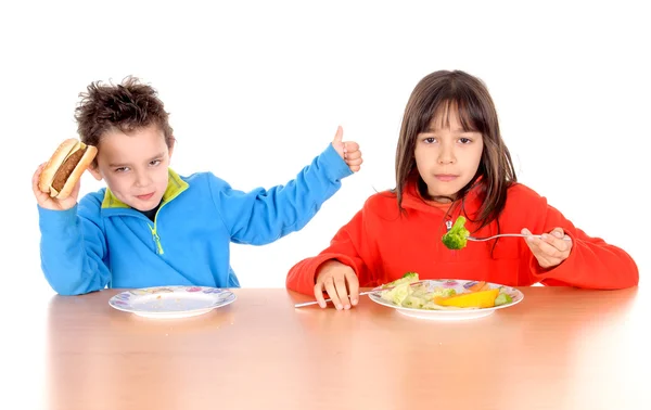 Niño y niña comiendo verduras y hamburguesas — Foto de Stock
