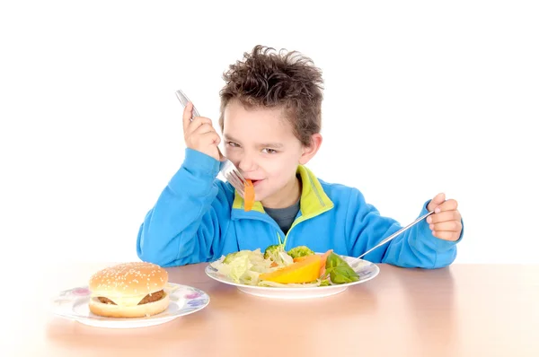 Niño desgarrado entre verduras y hamburguesa — Foto de Stock