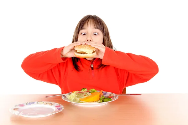 Meisje verscheurd tussen hamburger en groenten — Stockfoto
