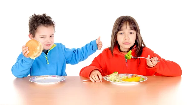 Niño y niña comiendo hamburguesa y verduras — Foto de Stock