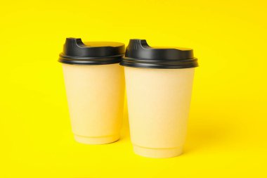 Sarı arkaplanda kağıt bardaklar, metin için boşluk