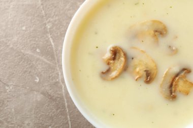 Gri arka planda bir kase lezzetli mantar çorbası