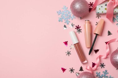 Pembe arka planda kozmetik ve Noel aksesuarları