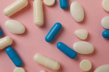 Pembe arka planda farklı haplar, üst görünüm