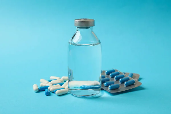 Pills and bottle with medicine on blue background