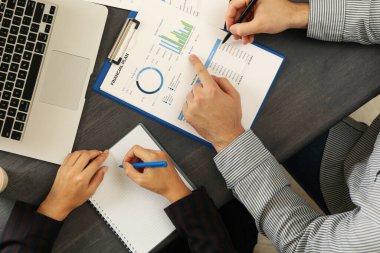 İş ortakları siyah ahşap masa üzerinde finansal planlama yapıyor.