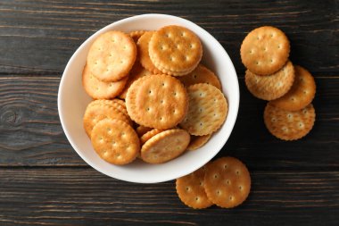 Tahta arka planda lezzetli kraker bisküvileri olan bir kase.