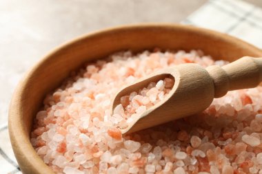 Bir kase pembe himalaya tuzu, peçete ve gri arka planda kepçe