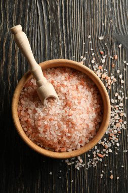 Bir kase pembe himalaya tuzu ve kepçeyle ahşap masada