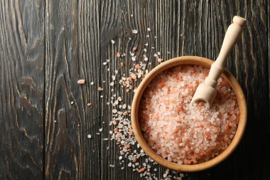 Bir kase pembe himalaya tuzu ve kepçeyle ahşap masada