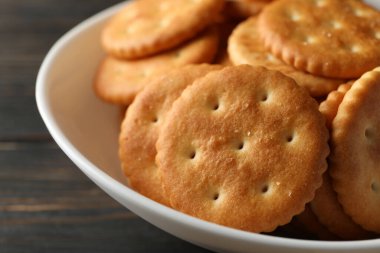 Tahta arka planda lezzetli kraker bisküvileri olan bir kase.