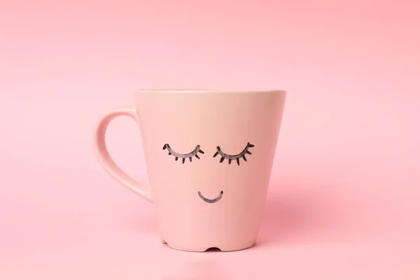 Cup with happy face on pink background