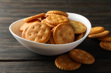 Tahta arka planda lezzetli kraker bisküvileri olan bir kase.