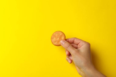 Sarı arka planda kadın eli kraker bisküvisi