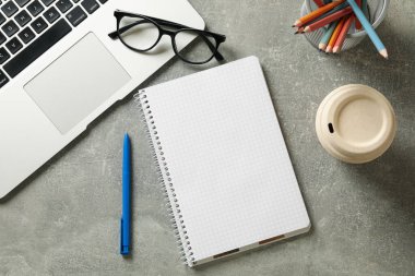 Gri arkaplanda boş not defteri olan işyeri, üst görünüm