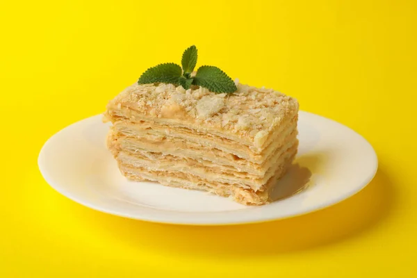 Plate with delicious Napoleon cake on yellow background