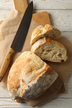 Beyaz ahşap zemin üzerinde ekmek ve bıçak olan kağıt fırını.