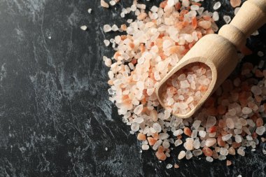 Siyah dumanlı arka planda pembe himalaya tuzu ile ahşap kepçe