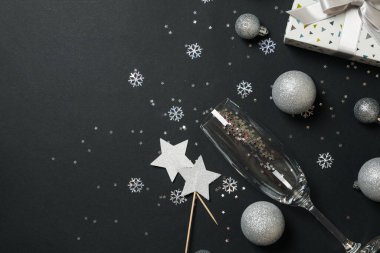 Yeni yıl aksesuarları ve siyah arka planda şampanya bardağı.