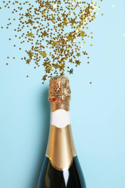 Mavi arka planda bir şişe şampanya ve parıltı.