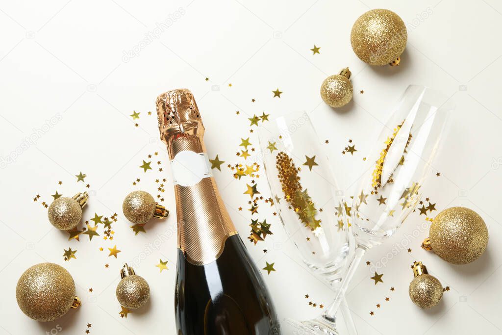 Champagne and glitter on white background, top view