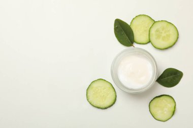 Beyaz arka planda bir kavanoz kozmetik krem ve salatalık dilimleri.