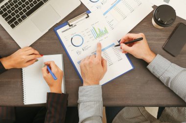 İş ortakları siyah ahşap masa üzerinde finansal planlama yapıyor.