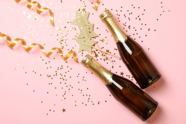 Pembe arka planda şampanya ve parıltı şişeleri