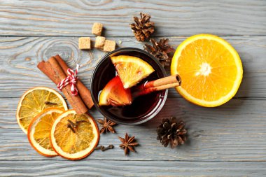 Gri ahşap masada bir bardak sıcak şarap ve malzemeler.