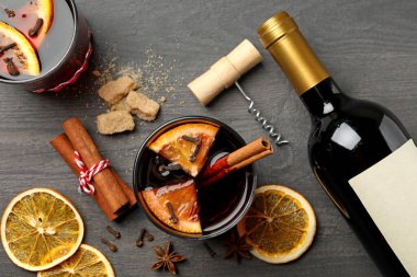 Bir şişe şarap, bir fincan sıcak şarap ve ahşap arka planda malzemeler.