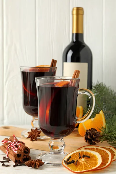 Bottle of wine, cups of mulled wine and ingredients on wooden background
