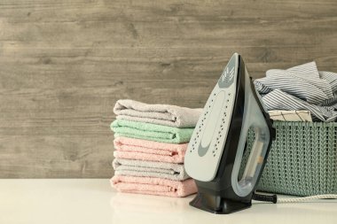 Demir, çamaşır sepeti ve ahşap arka planda bir havlu yığını