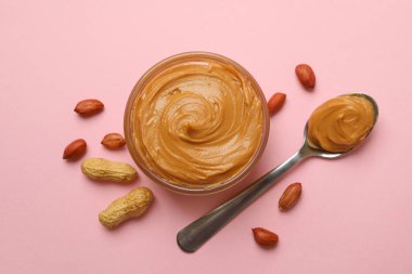 Fıstık, kase ve kaşık pembe arka planda fıstık ezmeli.