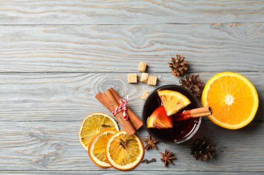 Gri ahşap masada bir bardak sıcak şarap ve malzemeler.