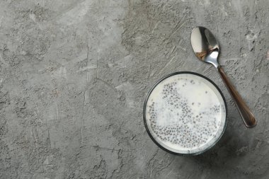 Gri arka planda chia pudingi olan kaşık ve bardak