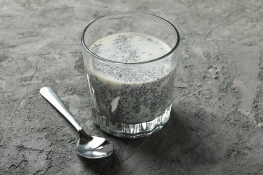 Gri arka planda chia pudingi olan kaşık ve bardak