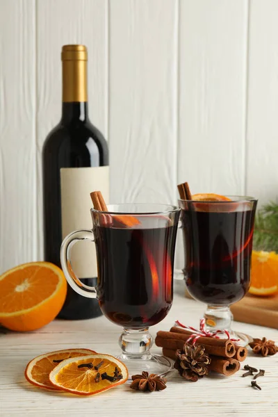 Bottle of wine, cups of mulled wine and ingredients on wooden background