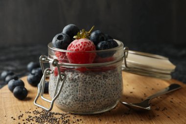 Siyah dumanlı masada bir kavanoz lezzetli chia pudingi.